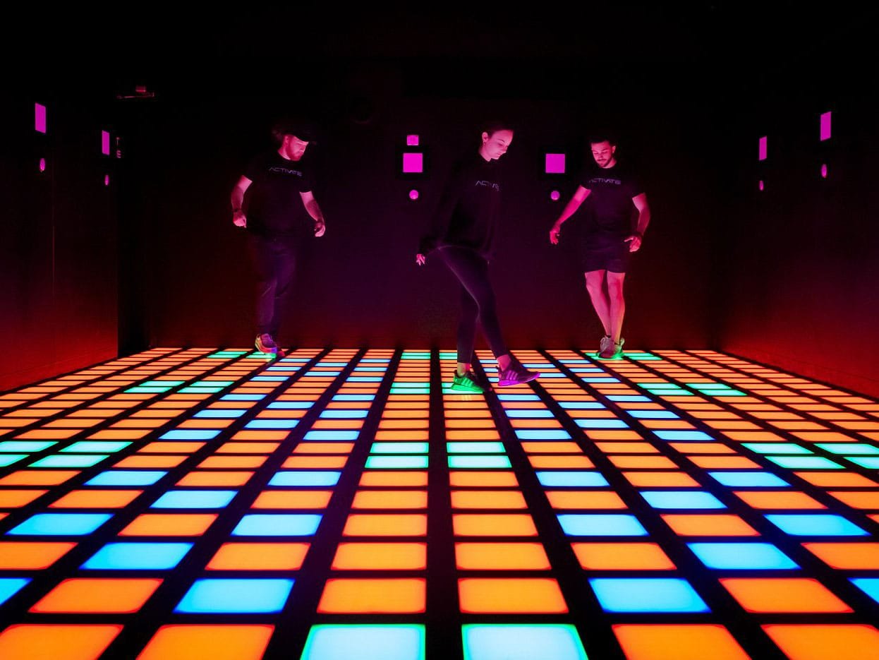 Trois joueurs profitant de l’interactive game floor dans une salle de divertissement