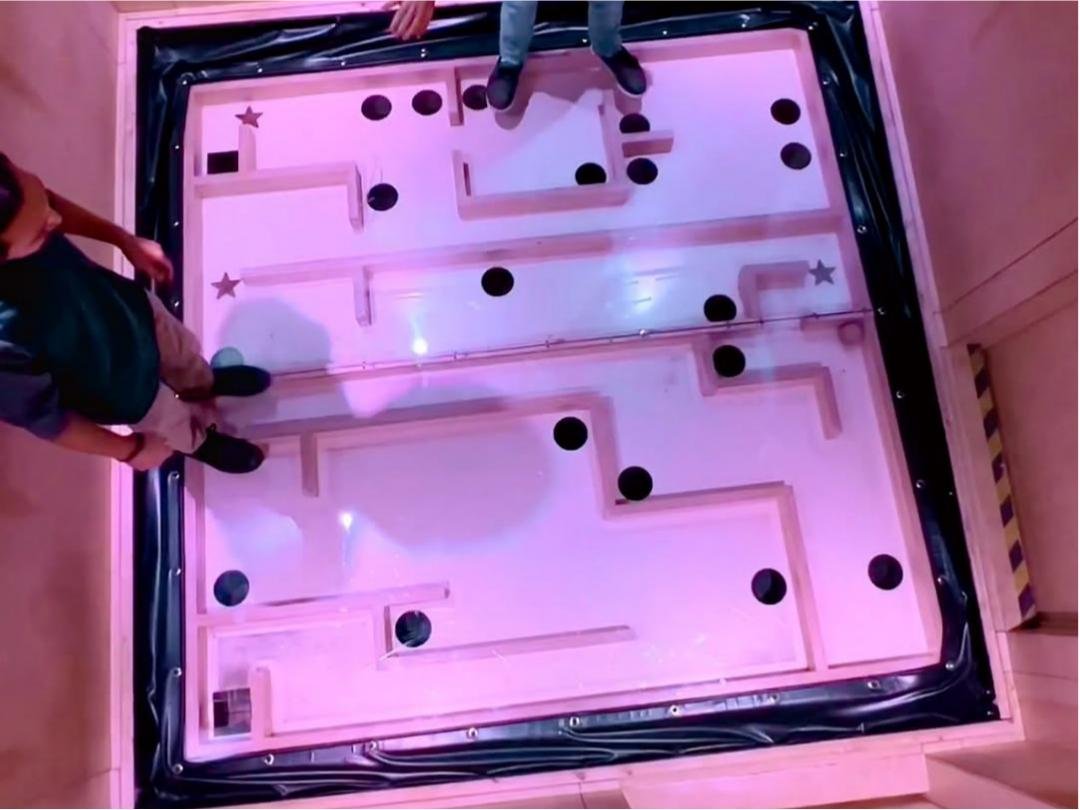 Two players are playing the Gravity Maze Challenge, cooperating to control the center of gravity.