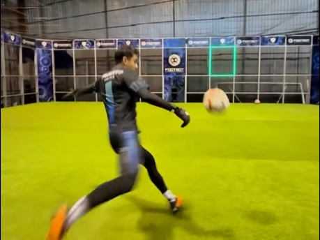 A player is accurately kicking the soccer ball into the goal.