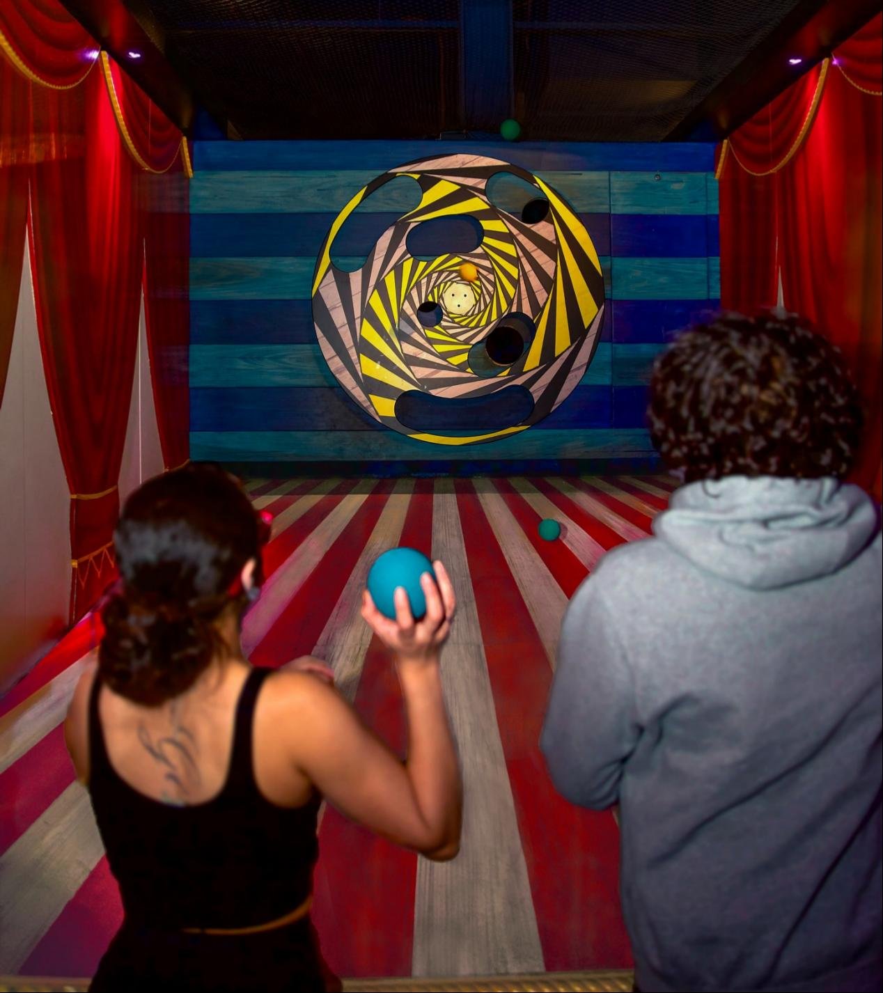 Two players aim at the holes in the spinning wheel and precisely throw the ball into the holes.