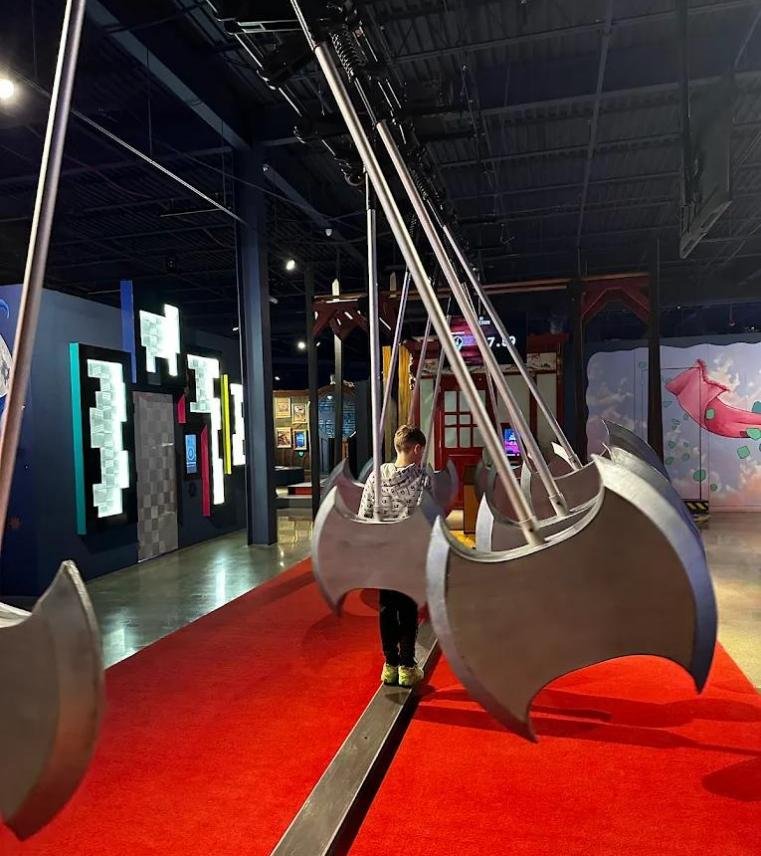 A player navigating across a balance bridge while dodging giant swinging axes in an Axe Dodge challenge room.