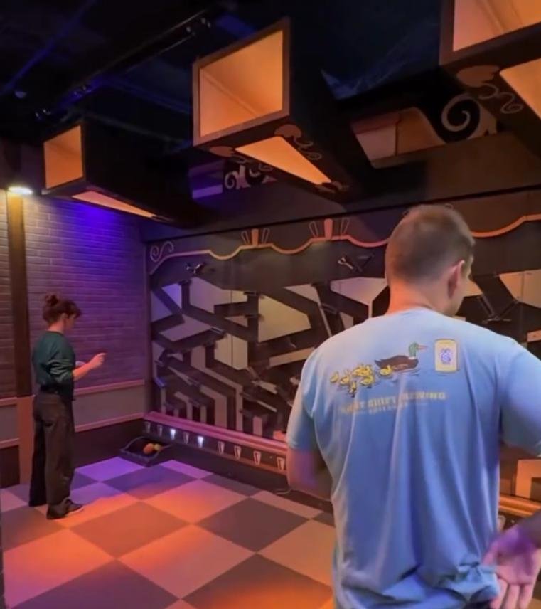 Players moving adjustable wall track pieces to guide balls into the bottom collection box in a Ball Recycling Challenge room.